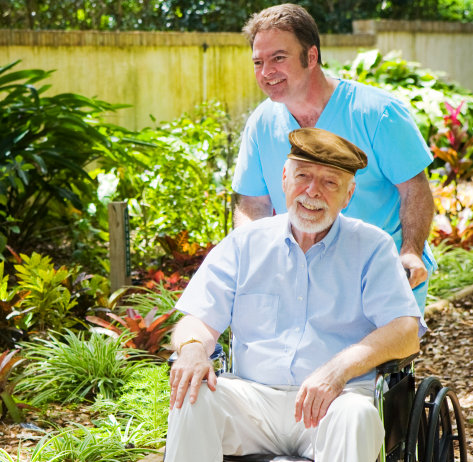 happy elderly man in wheelchair with his caretaker